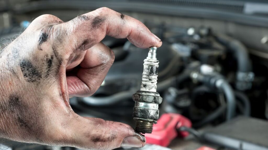 A man holding a spark plug, ready to fix a vehicle or electrical equipment.